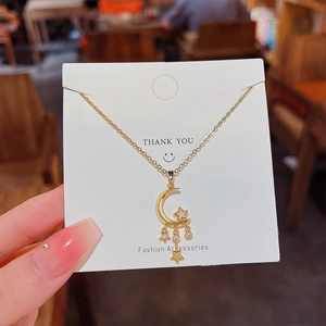 Detail of a gold moon and stars pendant necklace with tassels and zircon stones