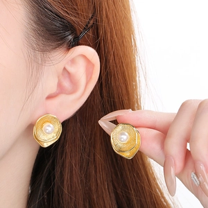 Close-up of French vintage gold spiral earrings with white pearl inlay worn by a model