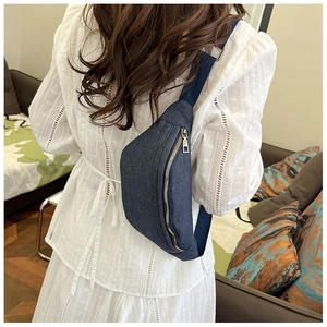 Detailed view of deep blue denim waist bag with golden zippers worn by a model