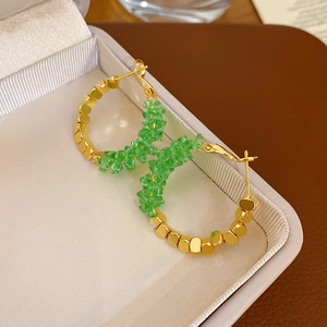 Macro detail view of elegant green crystal and gold beaded hoop earrings in jewelry box