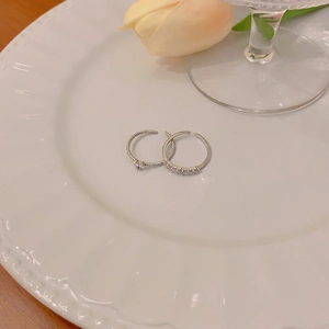 Detail of silver rings set with zircon stones on a white plate with tulips