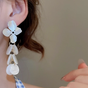 Detail of floral stud with white shell-textured resin discs on gold hanging earrings