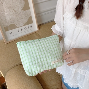 Close-up of a green checkered cosmetic bag with soft wavy texture and Sorukka label