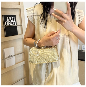 Detail of golden sequin evening clutch bag with detachable metal chain strap held by a model
