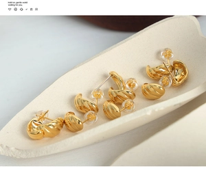 Detailed view of three pairs of gold-plated twisted hoop earrings on a display tray