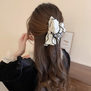 Detail of fabric bow hair claw clip with pearls worn on wavy long brown hair
