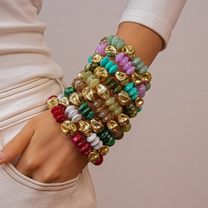 Close-up of stacked bohemian bracelets with colorful acrylic beads and irregular gold accents