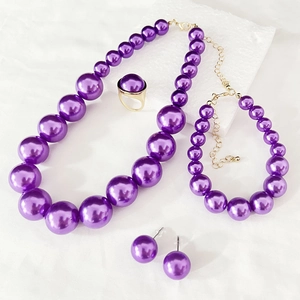 Detailed macro view of purple pearl necklace set with gold hardware on white surface