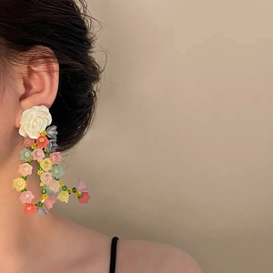 Elegant floral tassel earrings with pearls and colorful flowers worn by a female model