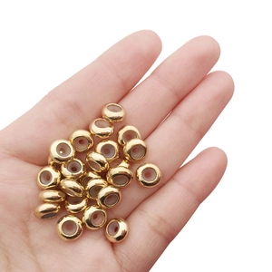 Makroaufnahme goldener Metallperlen mit weißer Silikoneinlage in einer offenen Hand