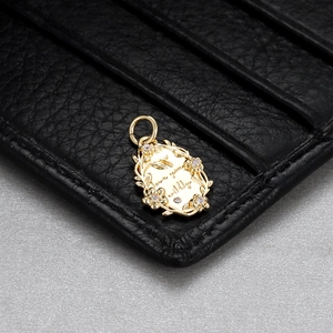 Macro detail of gold-plated oval pendant with floral carving and love you fully engraving