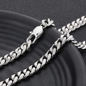 Macro detail of a silver stainless steel Cuban curb chain with a lobster clasp
