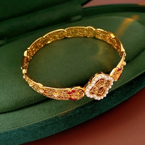 Detail of vintage gold brushed cuff bracelet with white pearls and rubies in green velvet box