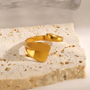 Polished gold geometric open ring with minimalist sculptural design on beige stone