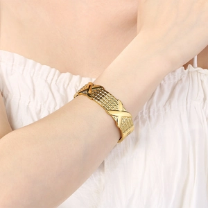 Close-up of 18K gold plated stainless steel bracelet with X-shape and woven texture detail
