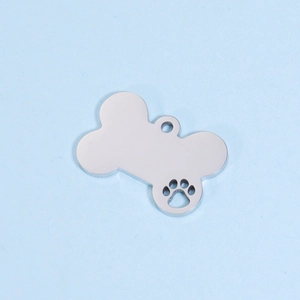 Close-up of a silver bone-shaped dog tag with a hollow paw print and polished finish