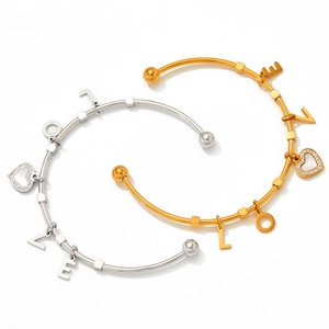 Detail of gold and silver stainless steel bangles with LOVE charms and heart pendant