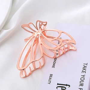 Macro shot of rose gold metal hollow butterfly hair claw clip on white satin fabric