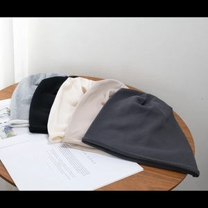Minimalist knitted slouchy beanie hats in multiple colors displayed on wooden table