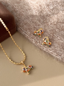 Detailed view of gold plated necklace and earrings set with zircon and pearls