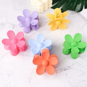 Flat lay of six colorful daisy flower hair claws on a premium marble surface background