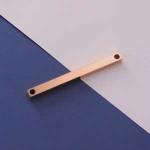 Macro view of rose gold stainless steel bar pendant with two mounting holes for DIY jewelry