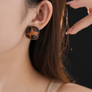 Gros plan de boucles d'oreilles carrées léopard élégantes en texture cuir marron
