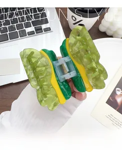 Detailed view of a green and yellow acetate butterfly hair claw clip with metal spring