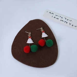 Detail view of asymmetric Christmas earrings with plush red and green pom poms