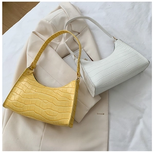 Detail of yellow and white faux crocodile texture crescent underarm bags on beige blazer