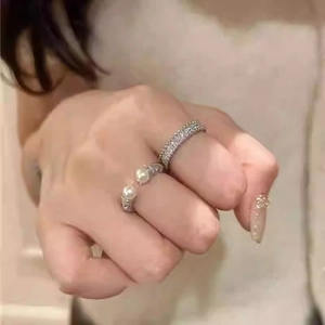 On-hand display of a silver pearl open ring and a sparkling zircon eternity band set