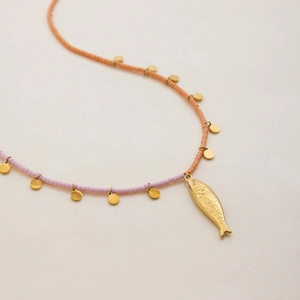 Detail of beaded necklace with orange and pink beads and a golden fish pendant