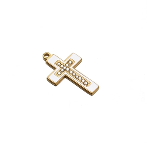 Macro detail of a gold cross pendant with white enamel inlay and sparkling rhinestones