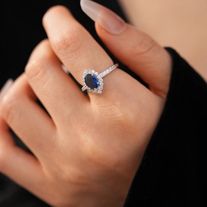 Macro view of blue sapphire halo ring featuring oval cut stone and pavé diamond band