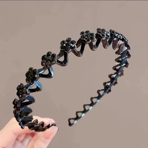 Detail of wavy black headband featuring delicate rhinestone floral accents for women