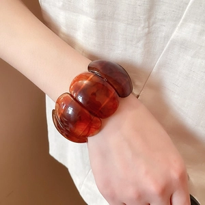 Close-up of wide amber resin wave bracelet showing tortoise shell texture and polished finish