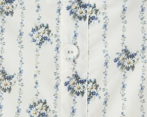 Detailed close-up of blue floral print fabric with white buttons and vertical pattern