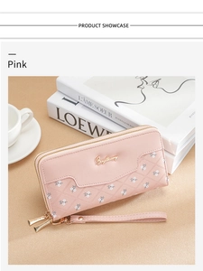 Detail of pink quilted long wallet with double zipper and floral pattern on a desk