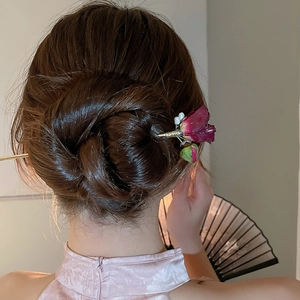 Dettaglio forcina per capelli con rosa rossa e perle in uno chignon vintage chic