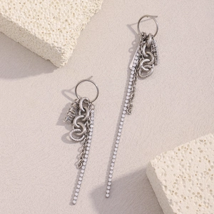 Detailed close-up of silver tassel earrings with zircons on a textured background
