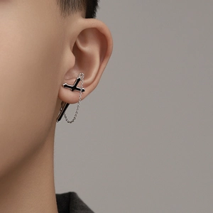 Close-up of a silver and black cross chain earring worn by a male model for a punk style look
