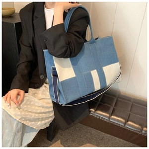 Detail of blue and beige patchwork tote bag with fabric shoulder strap on a model