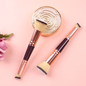 Dual-ended foundation brush with rose gold tubes on an elegant pink background