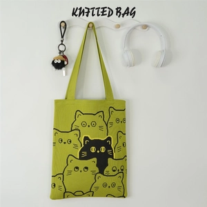 Detail of green knitted tote bag with cartoon cat patterns and soft fabric texture