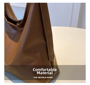 Detail of brown leather tote showing fine stitching, adjustable strap, and magnetic buckle