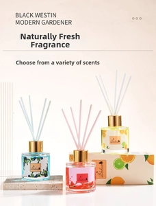 Three fruit-scented reed diffusers with gold caps and colorful fiber sticks in a gift box