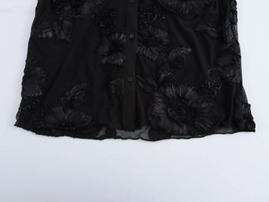 Detail of 3D floral appliques on black mesh shirt with button-front closure