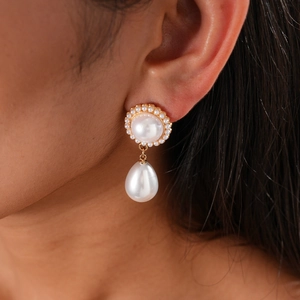 Close-up of vintage teardrop pearl earring with golden finish worn by a model