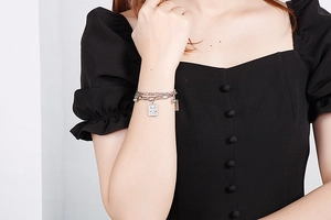 Silver double layer chain bracelet with square poker pendant on model's wrist