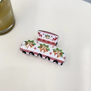 Detailed view of white Christmas claw clip featuring bells, holly leaves and reindeer patterns